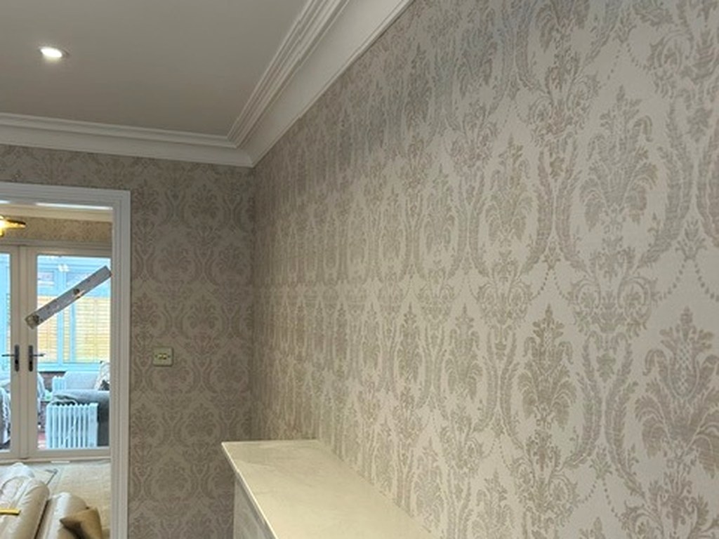 Damask wallpaper hung around a chimney breast and fireplace with white coving