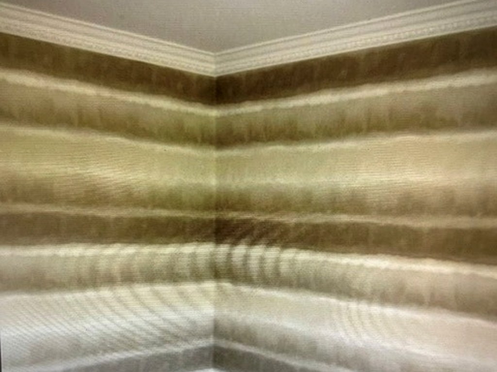 Horizontal ombre striped wallpaper hung around a room corner with matched pattern