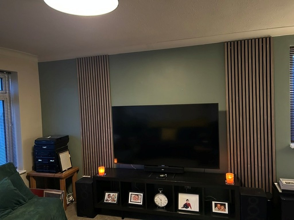 Lounge media wall painted sage green behind timber slat panelling