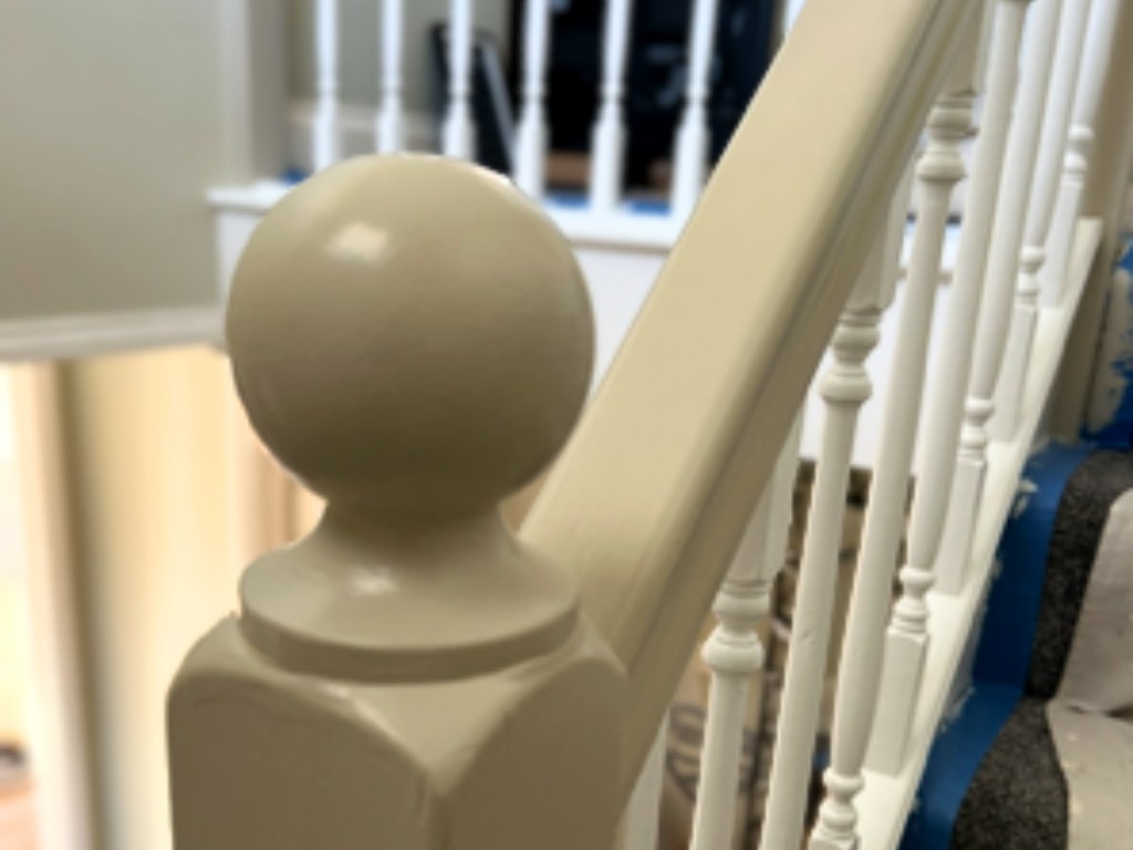 Staircase newel post and handrail freshly painted with a smooth satin finish