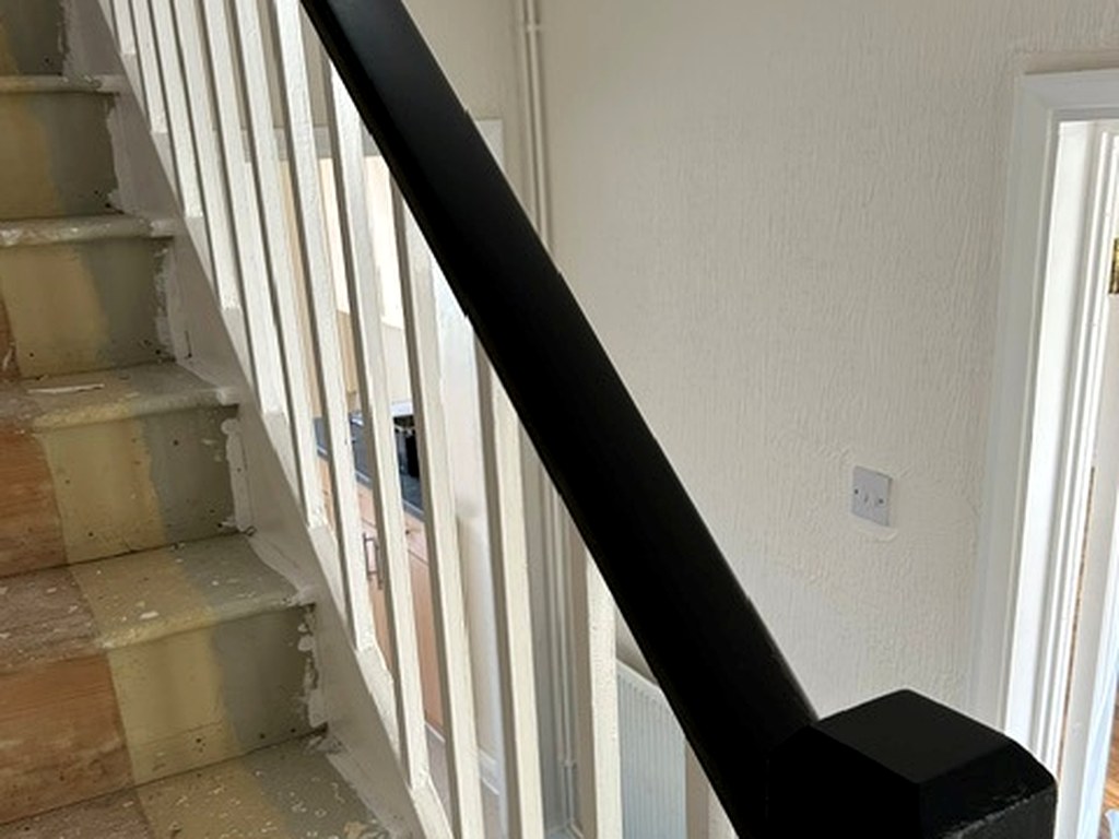 Staircase handrail and newel post finished in black with white spindles