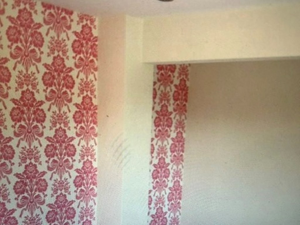 Bold red and cream damask wallpaper hung on a bedroom chimney breast